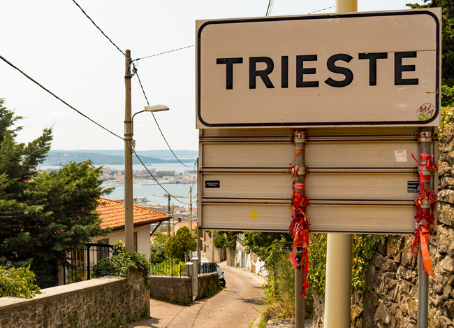 Meine Alpenüberquerung von Salzburg nach Triest 2019: "Geschafft - im doppelten Sinne des Wortes. Wer mag, kann das rote Bändchen, das Erkennungszeichen der Salzburg-Triest-Wanderer, ans Ortsschild binden."