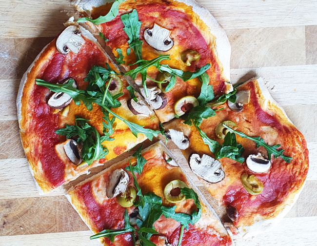 Vegane Pizza mit Champignons, Oliven, Rucola und Bohnen-Hummus