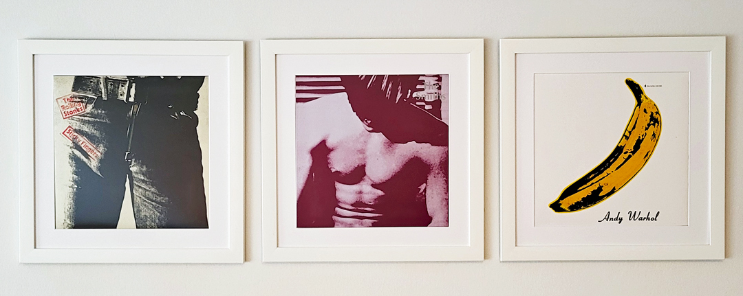 Drei ikonische Schallplattencover in weißen Holzrahmen – zwei von Andy Warhol gestaltet, eines aus seinem Umfeld.
