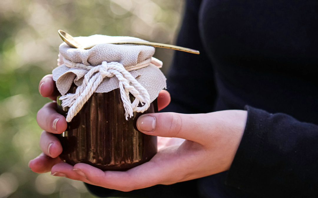 Zwei Hände halten ein mit Leinen und Kordel umwickeltes Marmeladenglas – Symbol für Einfachheit und bewusste Wahl.