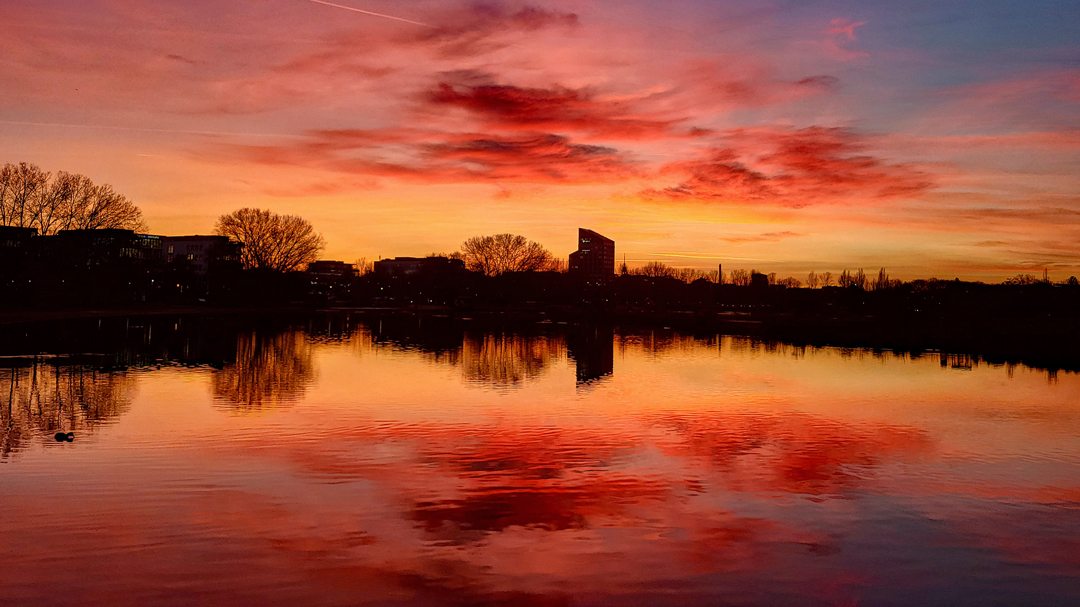 Sonnenuntergang am Wöhrder See in Nürnberg mit orangefarbenem Himmel und Spiegelung im Wasser